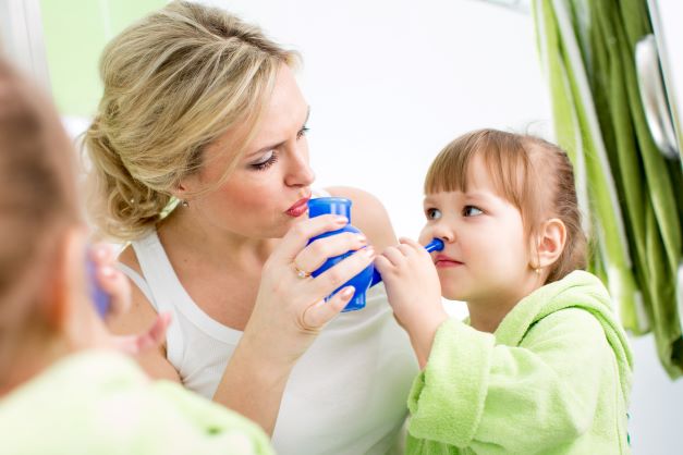 matka s holčičkou, která drží v ruce modrou konvičku na proplach nosu